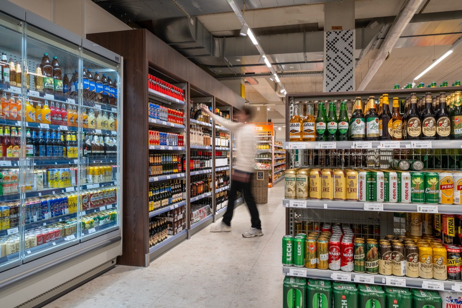 Het drankenschap in Tilburg: koelkasten vol flessen en blikken, en rechts de schappen met Oost-Europees bier van Lviv, Obolon, Kozel en Perla.