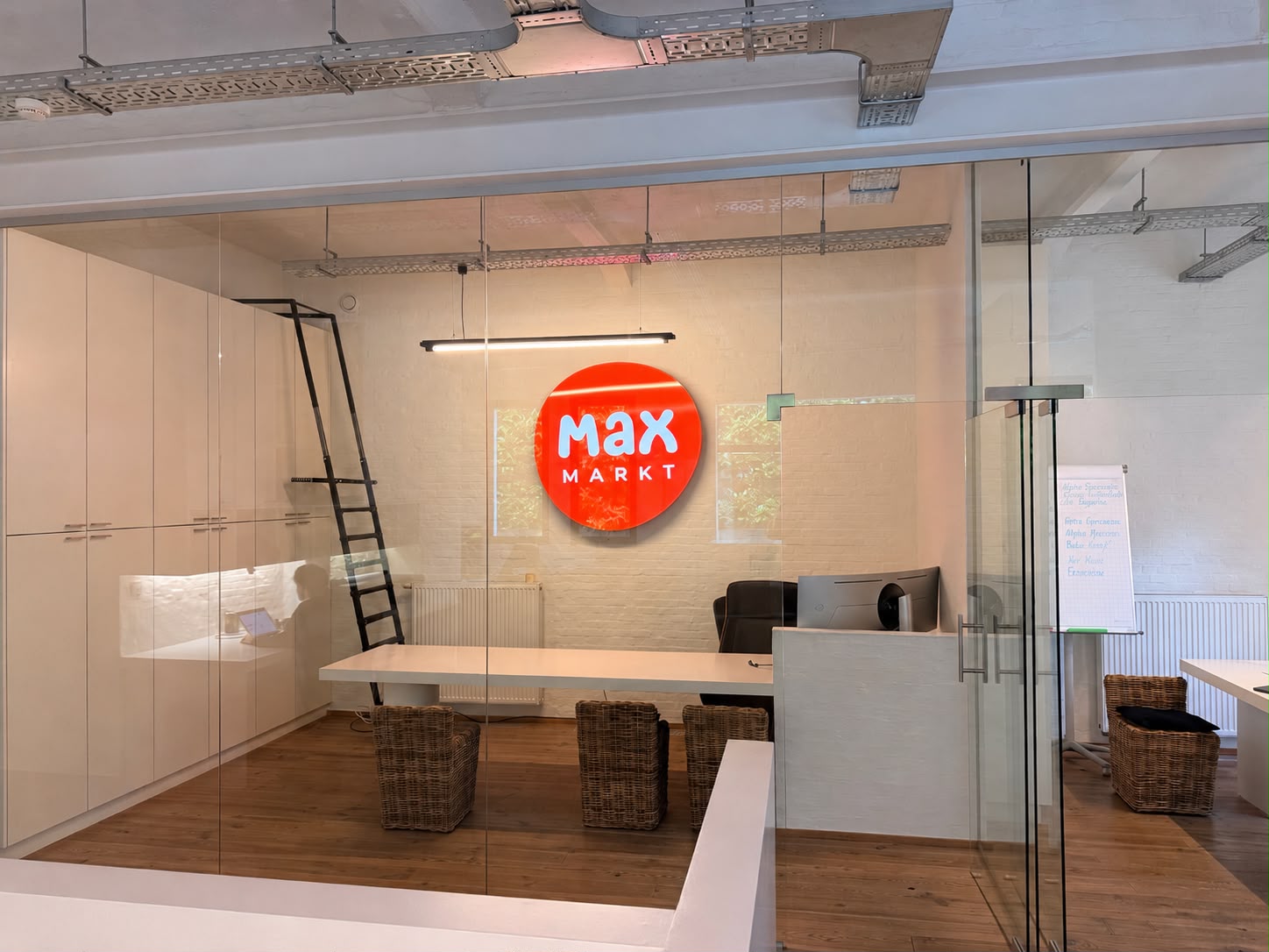 Het hoofdkantoor: het Max Markt-logo verlicht aan de witte bakstenen muur, achter glas.