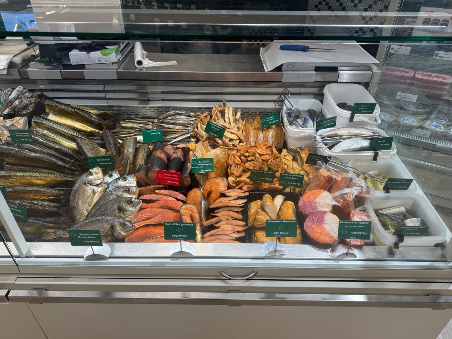 De gerookte toonbank in Tilburg: gerookte makreel, gerookte zalmfilet, koudgerookte dorade royal, gerookte garnalen, octopus en balyk achter het glas.